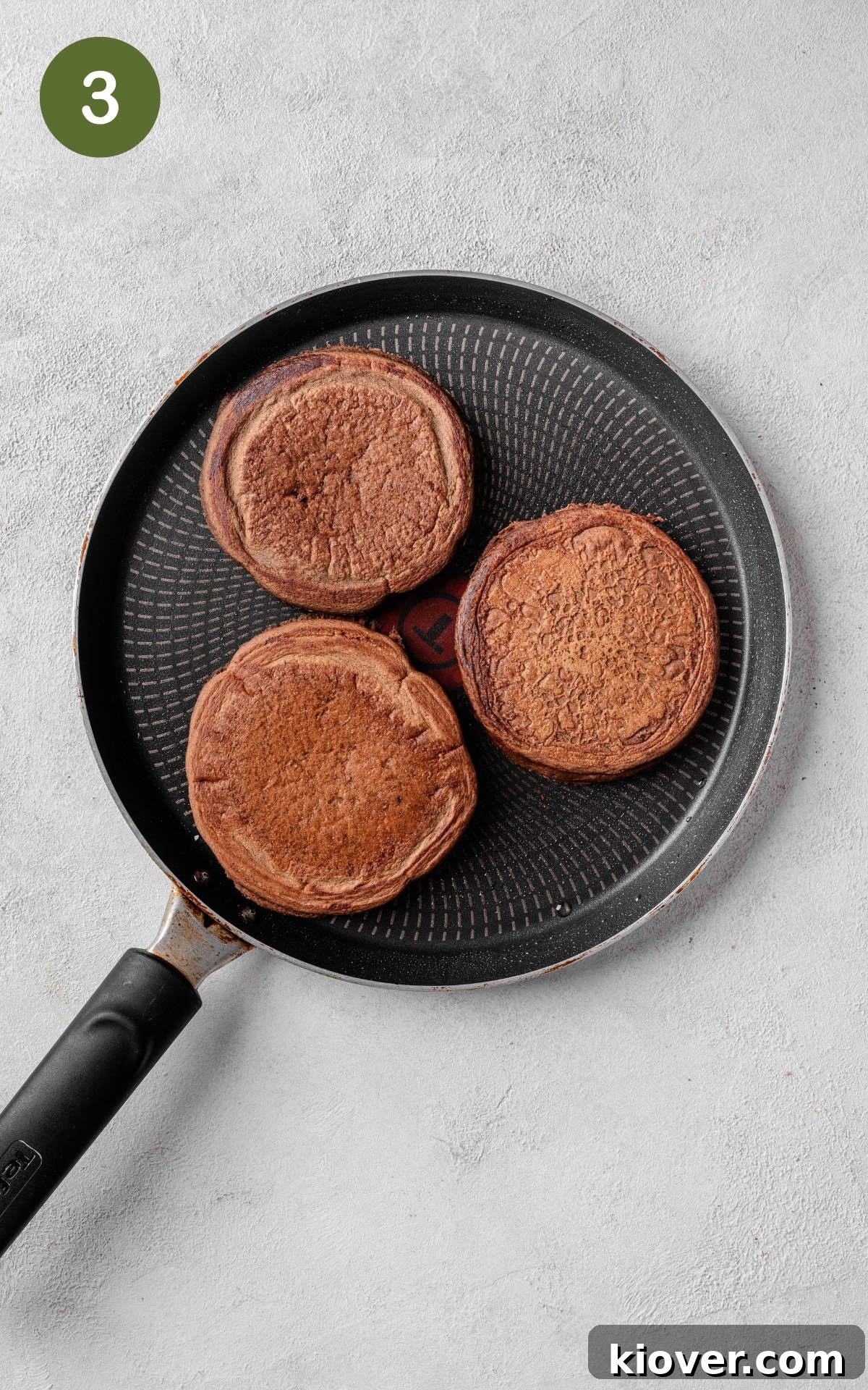 Decadent Chocolate Pancakes Recipe for Fluffy, Fudgy Stacks 6 3 pancakes in a skillet.