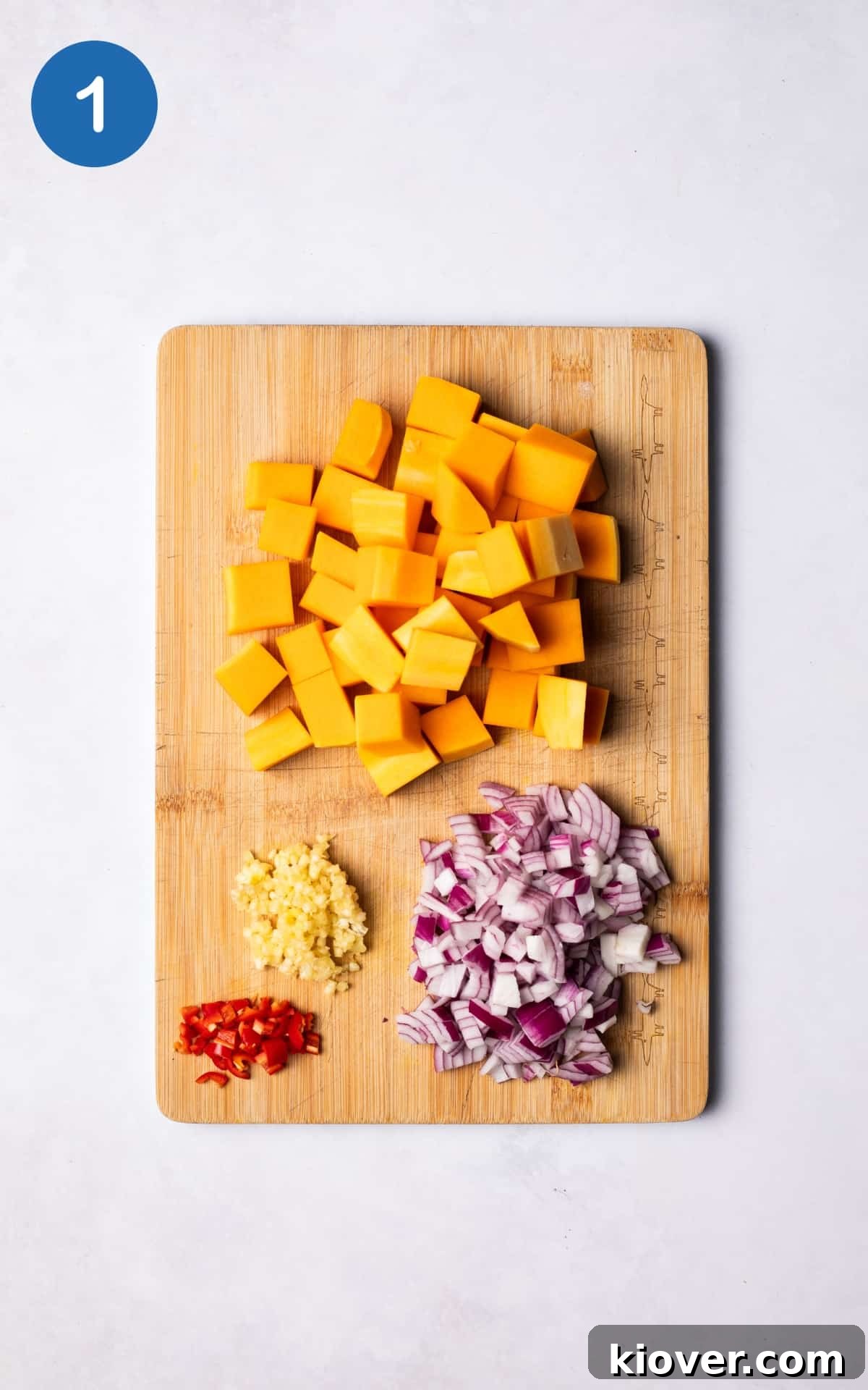 Butternut squash, red onion and red chilli on cutting board.