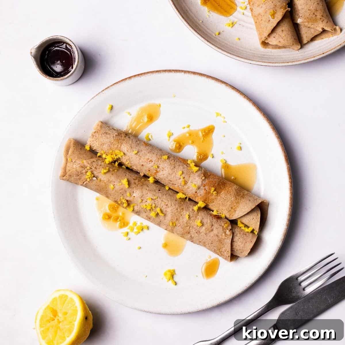 Gluten Free Crepes on a plate drizzled with maple syrup.