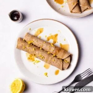 Gluten Free Crepes on a plate drizzled with maple syrup.