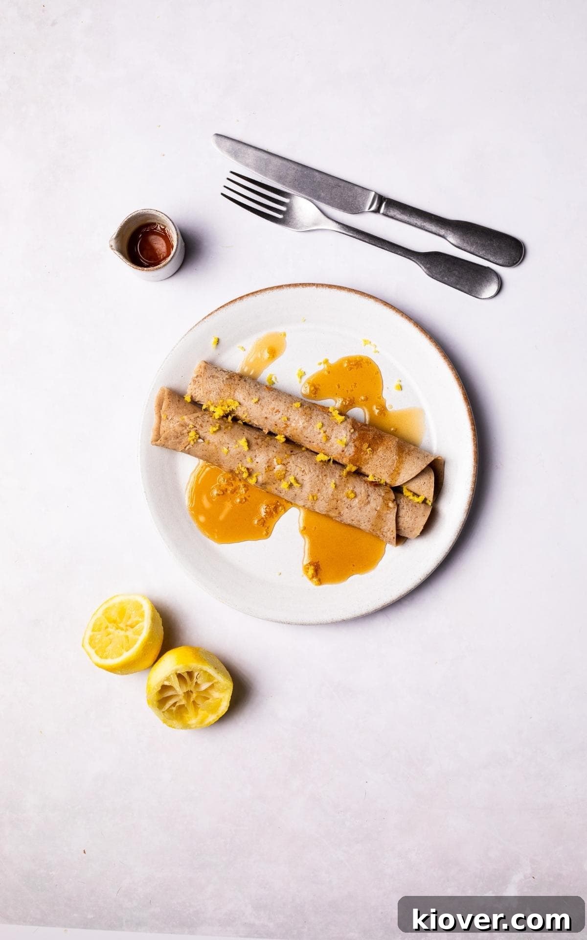 Gluten Free Crepes served on a plate with maple syrup and lemon zest.