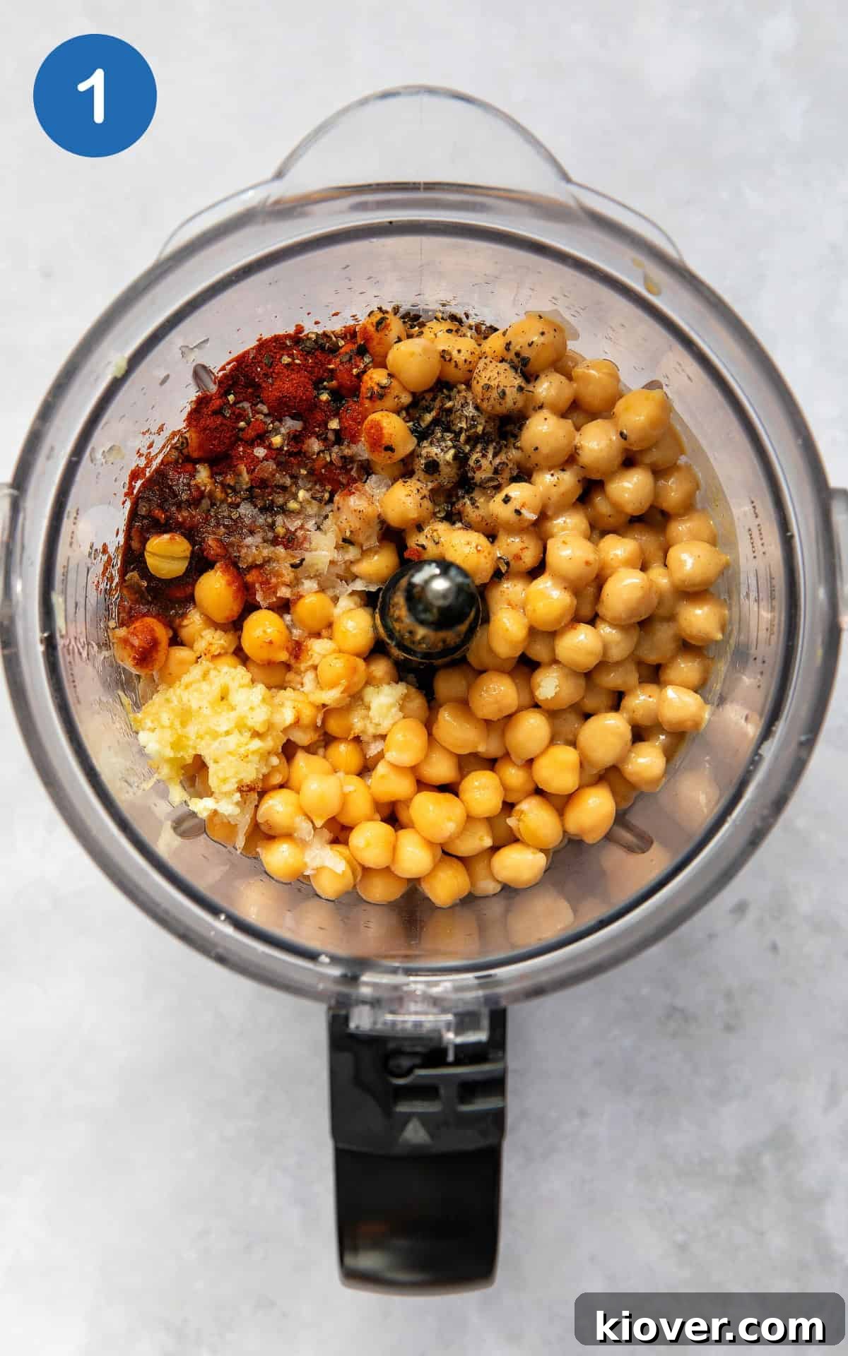 Creamy Garlic Hummus Recipe for Smooth, Flavorful Dip 4 chickpeas, garlic, paprika, lemon juice in a food processor ready to blend.