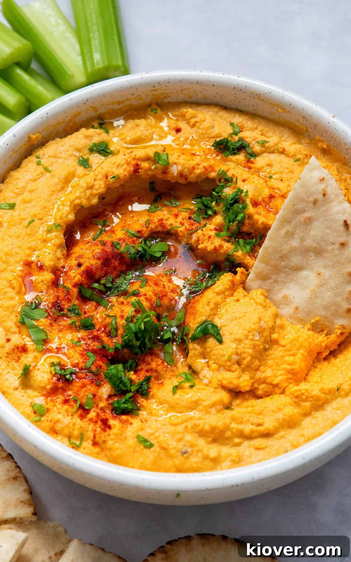 Creamy Garlic Hummus Recipe for Smooth, Flavorful Dip 7 garlic hummus closeup with a pitta, served in a white bowl ready to eat.