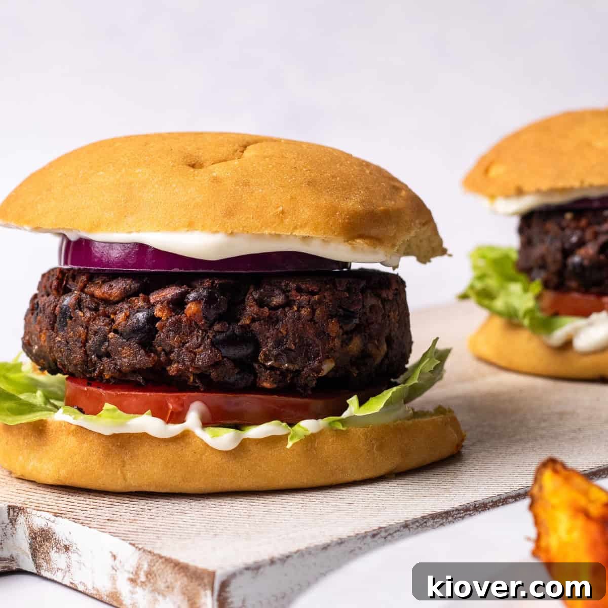 Juicy Portobello Mushroom Burger Recipe for Grill or Skillet 2 mushroom burgers in a bun with potato wedges on the side.