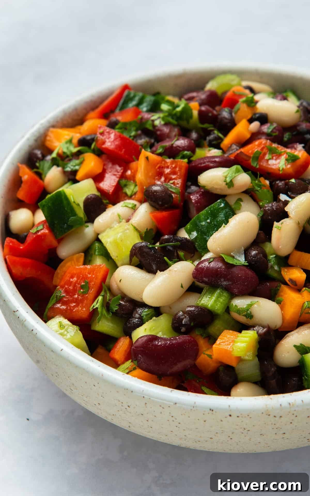 mixed bean salad in large grey bowl on white surface.
