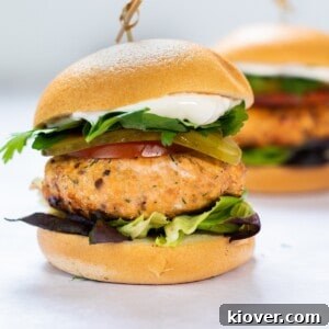 Grilled Salmon Burgers with Lemon-Dill Aioli 12 salmon burger with bun and lettuce on white background.