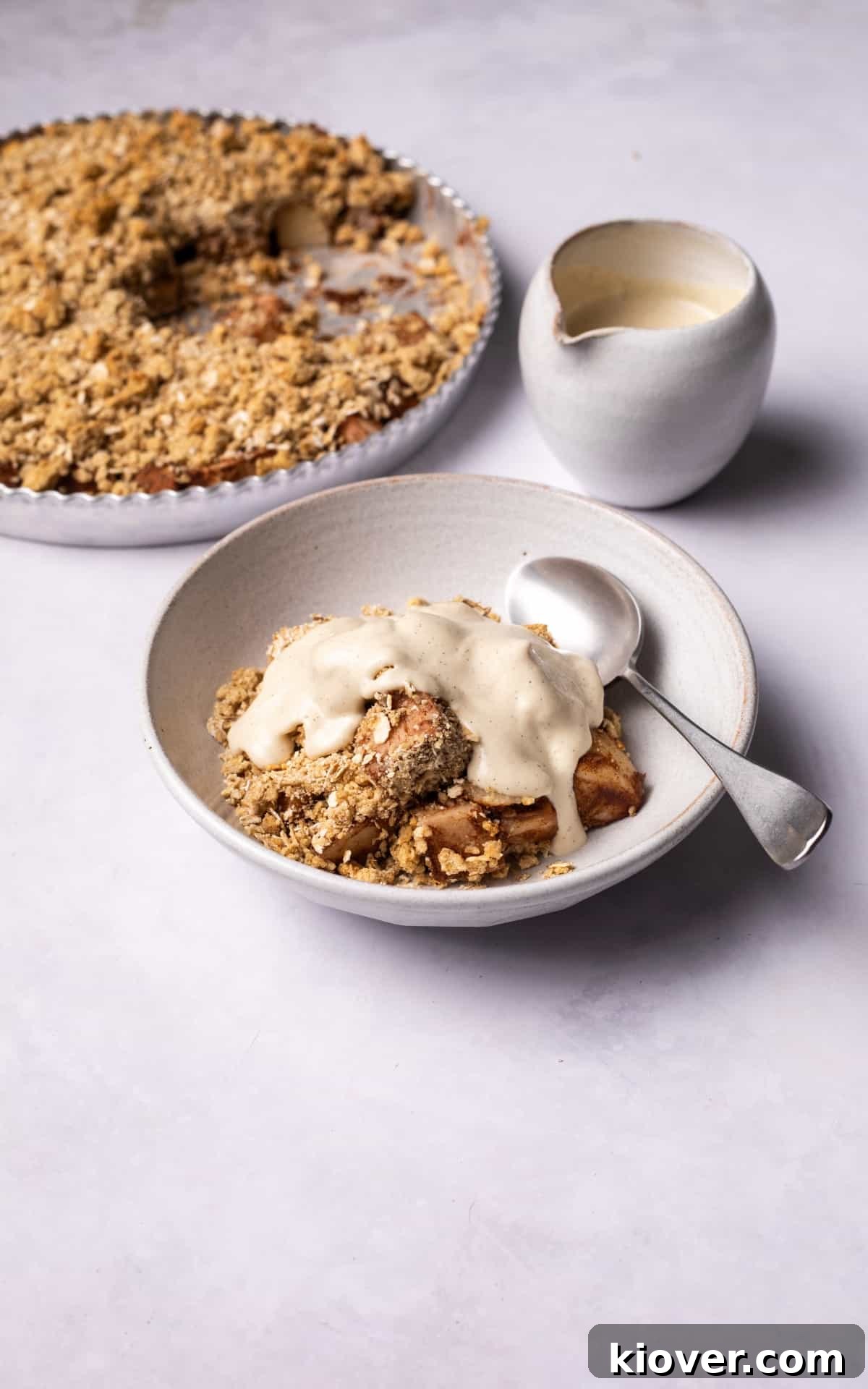 Pear crumble served in a bowl with vanilla cashew cream.