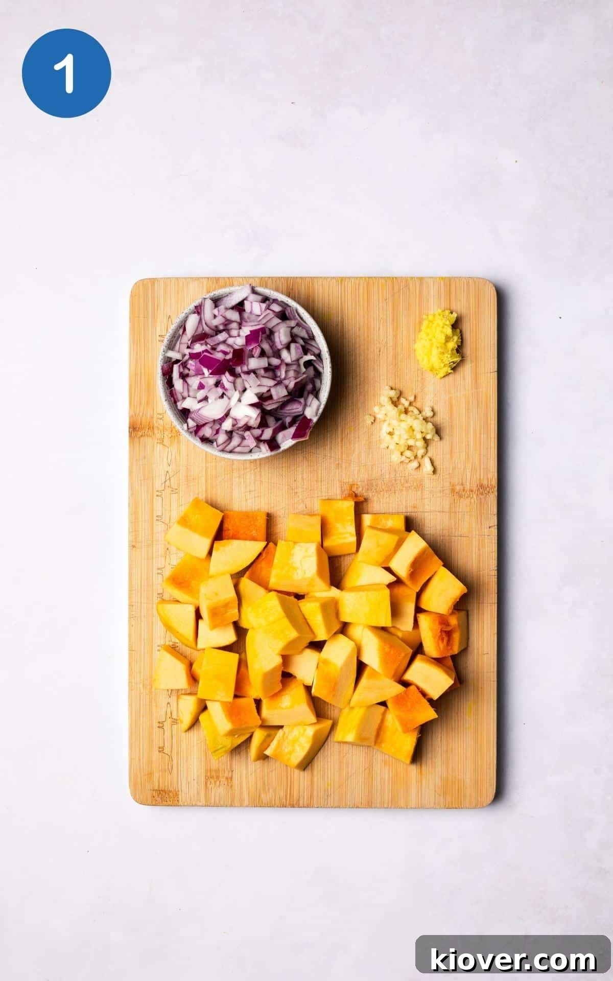 Creamy Pumpkin Curry Recipe with Coconut and Warm Spices 4 chopped pumpkin and onion on a wooden cutting board.