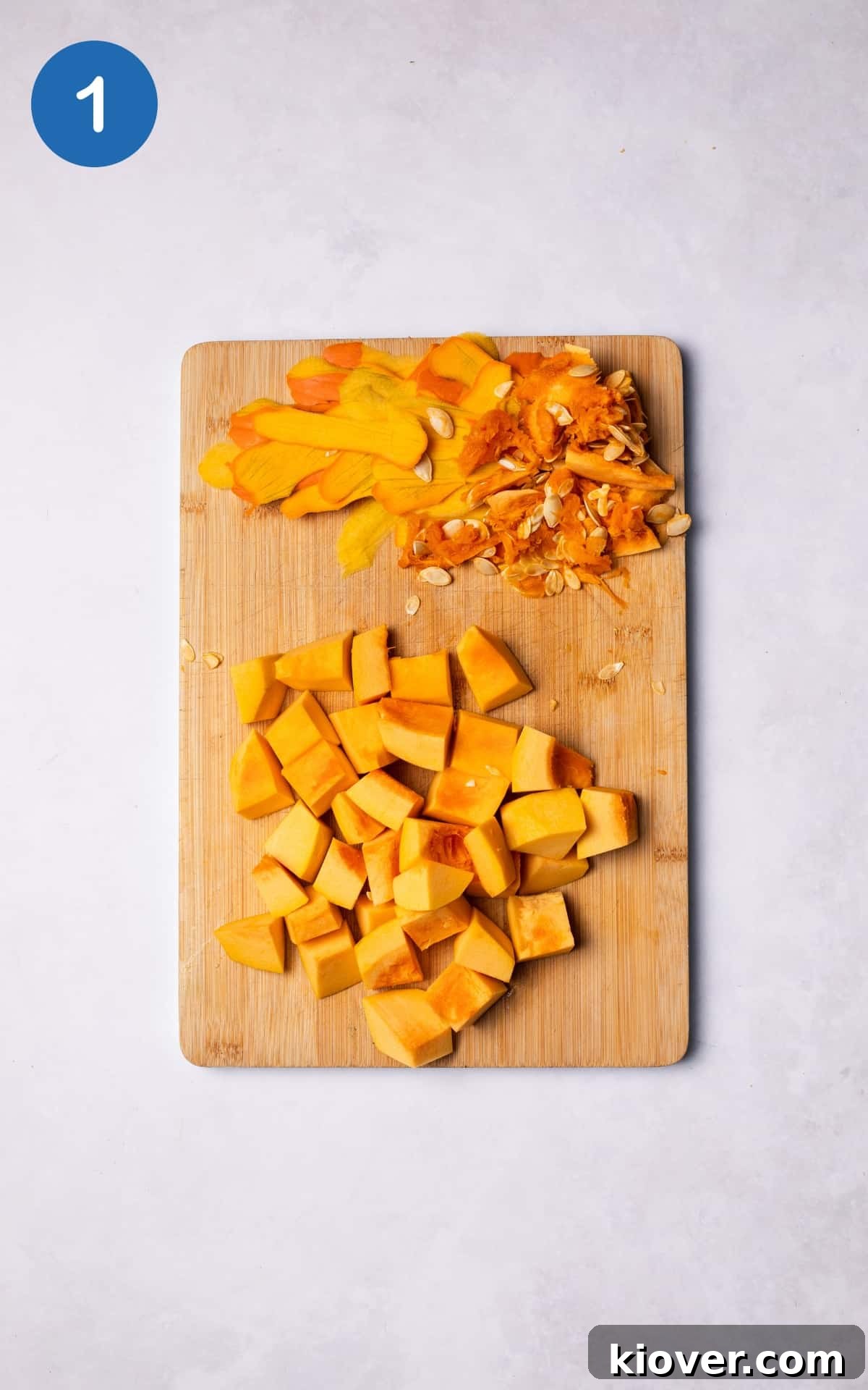 Pumpkin sliced into chunks on a wooden cutting board.