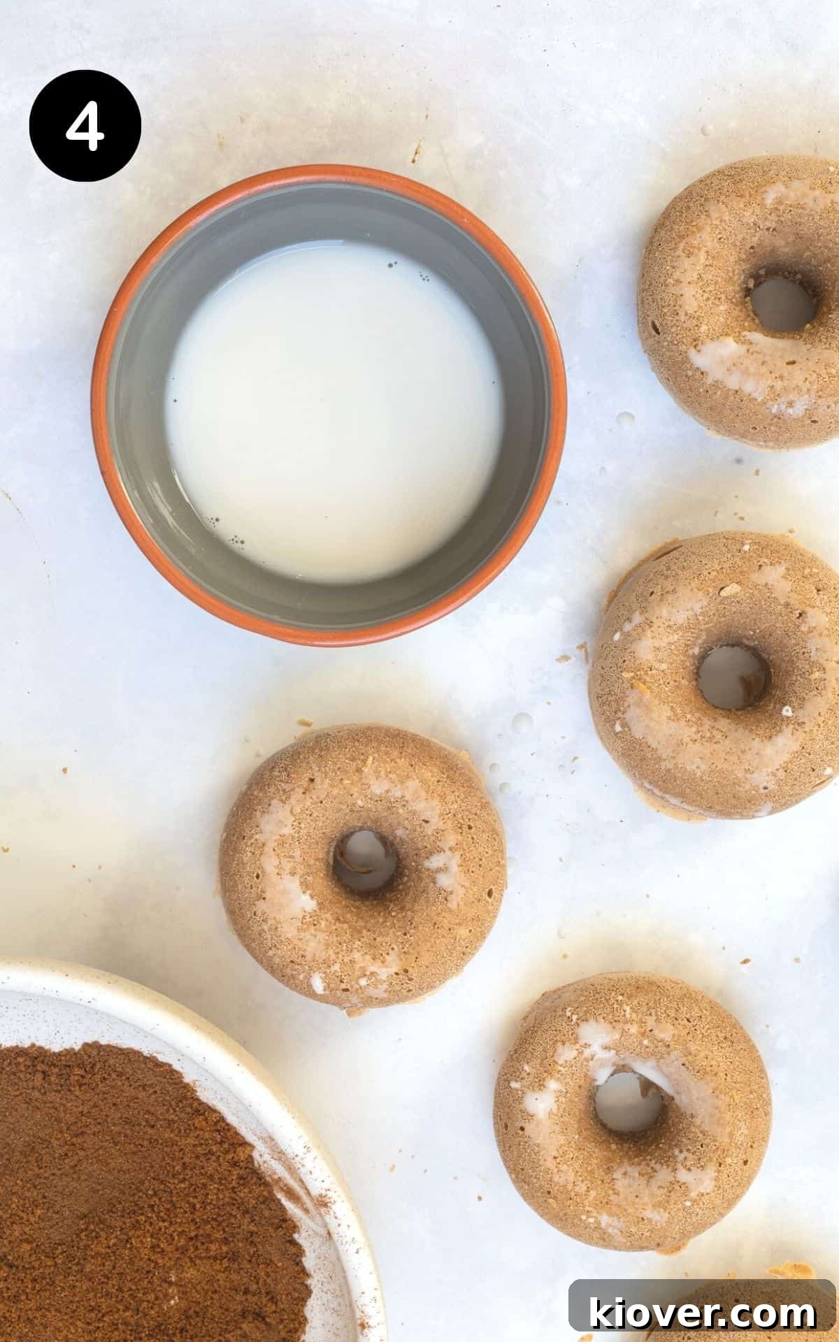 baked doughnuts on a white background dipped in milk.