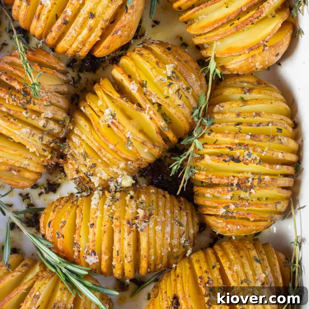Crispy Hasselback Potatoes with Garlic and Parmesan 2 top view of hasselbacks in white baking dish with herbed salt seasoning showing.