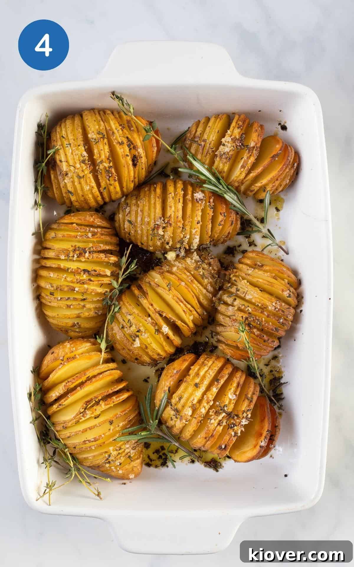 Crispy Hasselback Potatoes with Garlic and Parmesan 7 an overhead view of these roasted whole potatoes in a white baking dish seasoned with herb salt and olive oil.