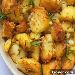rosemary infused roast potatoes in a baking dish on a white marble background