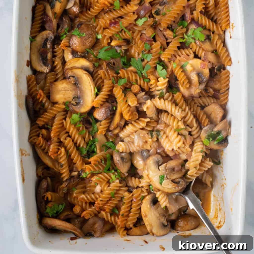 closeup of this vegan stroganoff recipe in white dish with silver serving spoon.