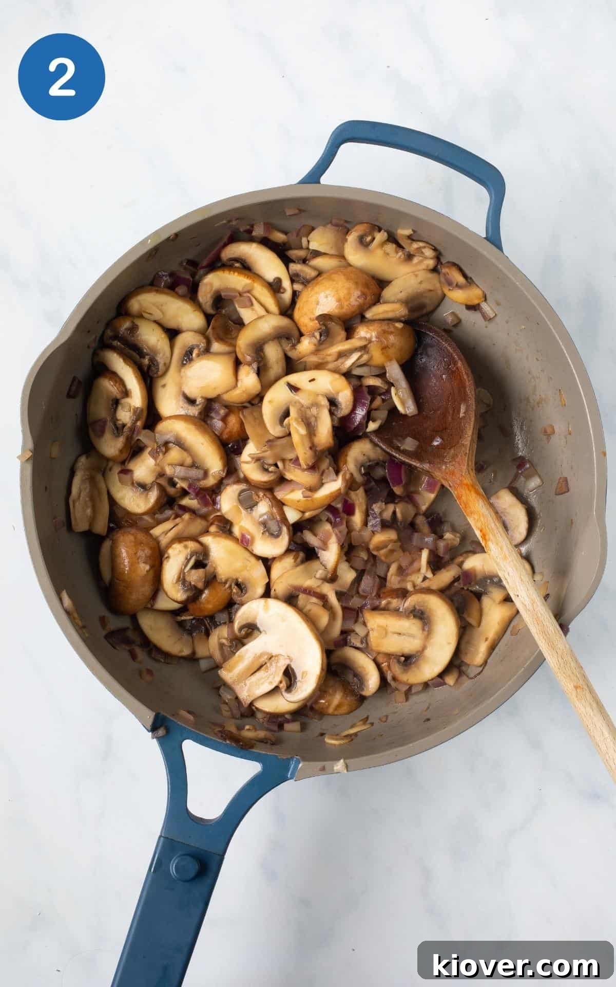 overhead view of diced garlic, onion, and mushrooms in a blue skillet.