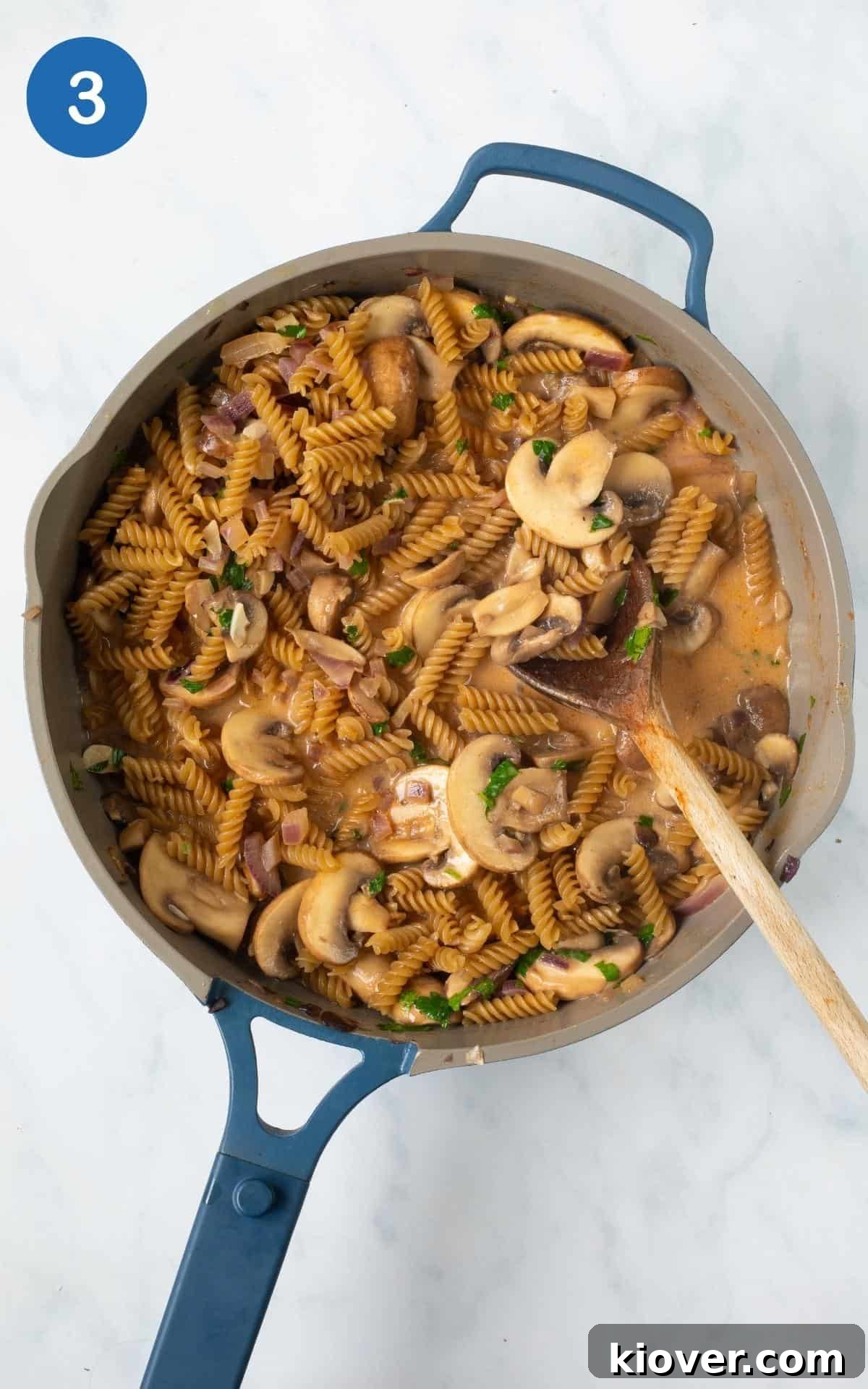overhead view of this Mushroom Stroganoff Pasta Bake in a blue skillet with a wooden spoon.