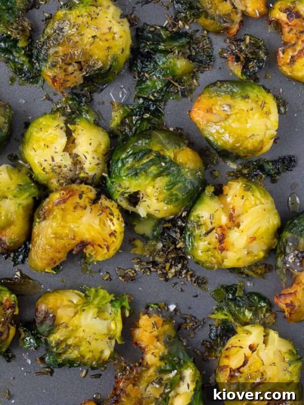 crispy brussel sprouts on grey baking tray with herbs on top.