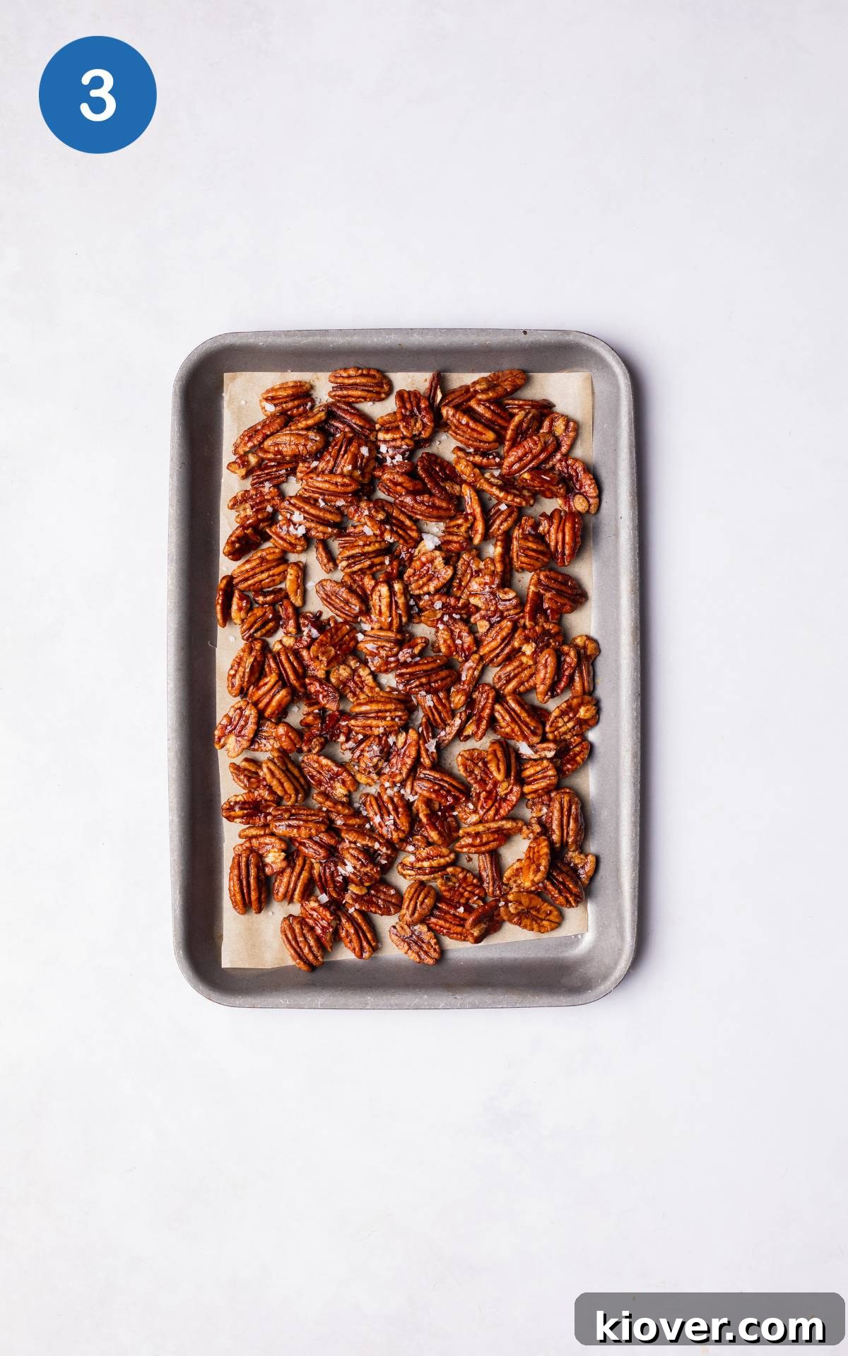 Sweet Cinnamon Candied Pecans Recipe for Gift Giving 6 Pecans on a lined baking tray sprinkled with salt.