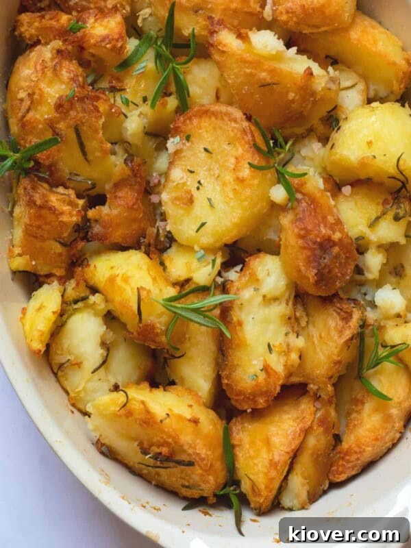 rosemary infused roast potatoes in a baking dish on a white marble background