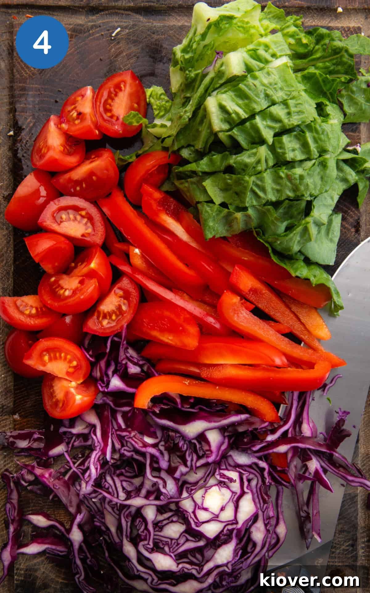 lettuce, red pepper, cabbage and tomatoes on a cutting board.