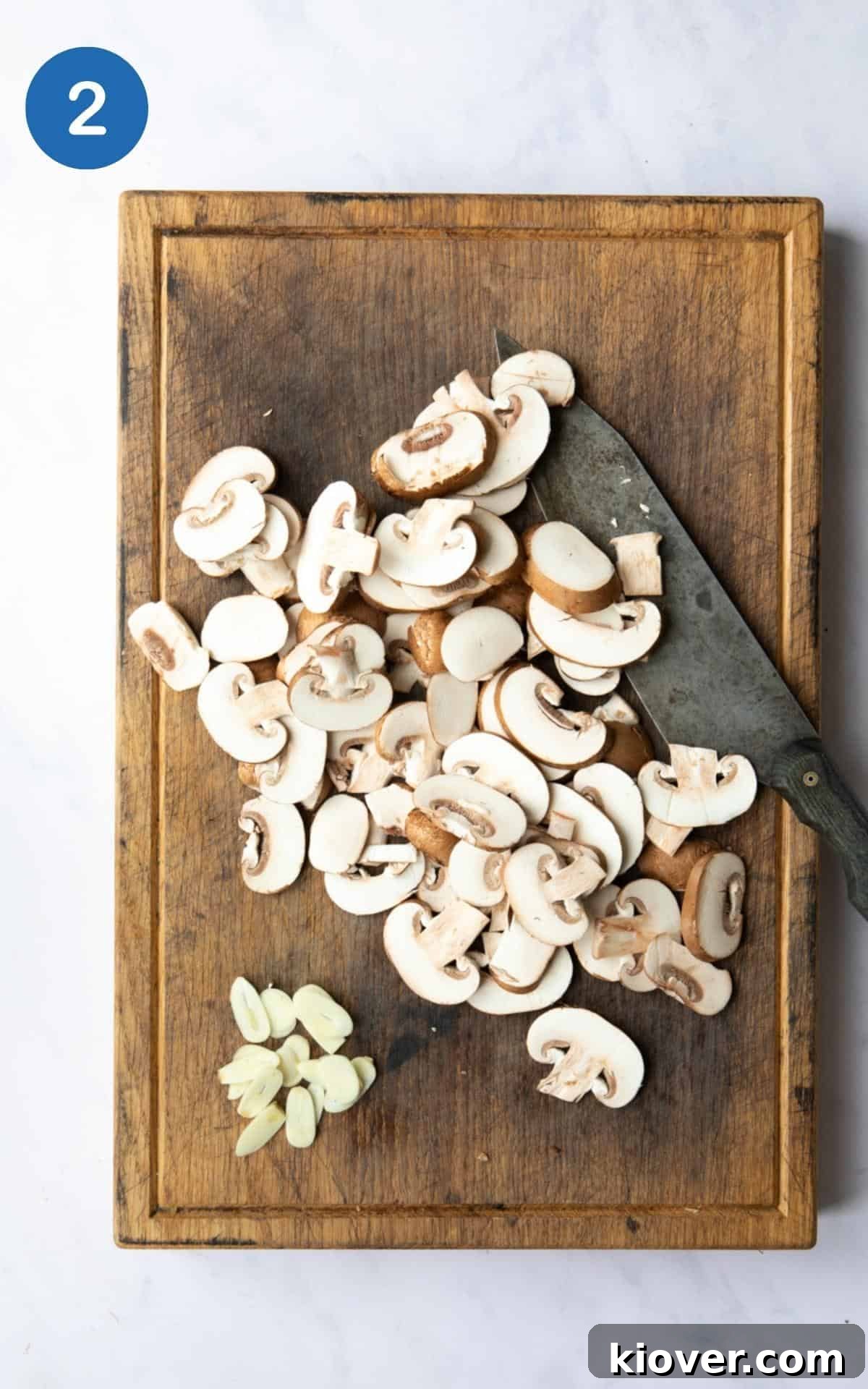 Creamy Vegan Mushroom Pasta Recipe for Dinner Nights 5 Sliced mushrooms and garlic on a chopping board.