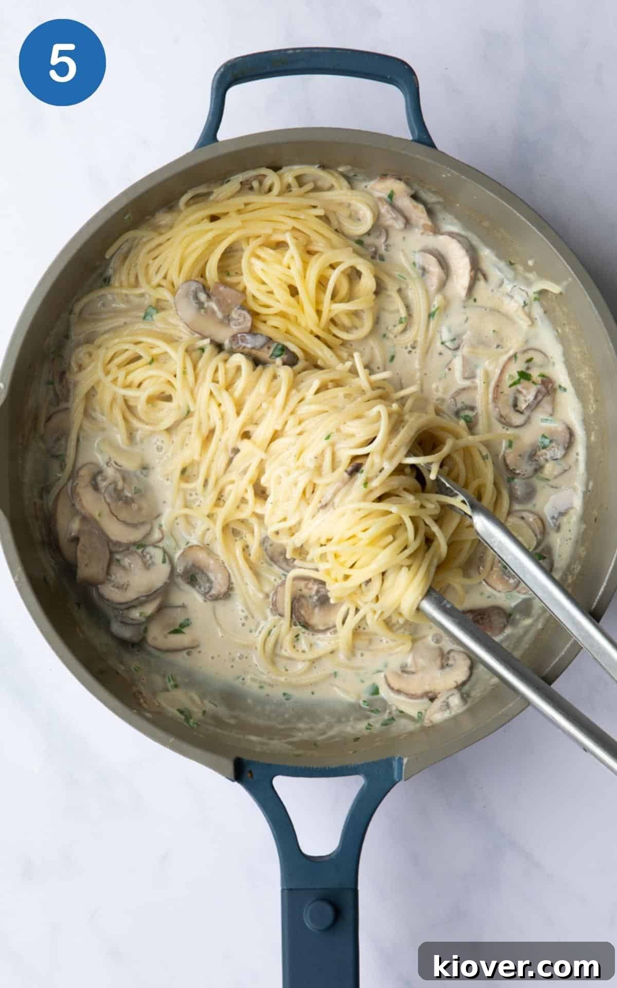 Creamy Vegan Mushroom Pasta Recipe for Dinner Nights 8 Pasta being mixed into creamy mushrooms with tongs.