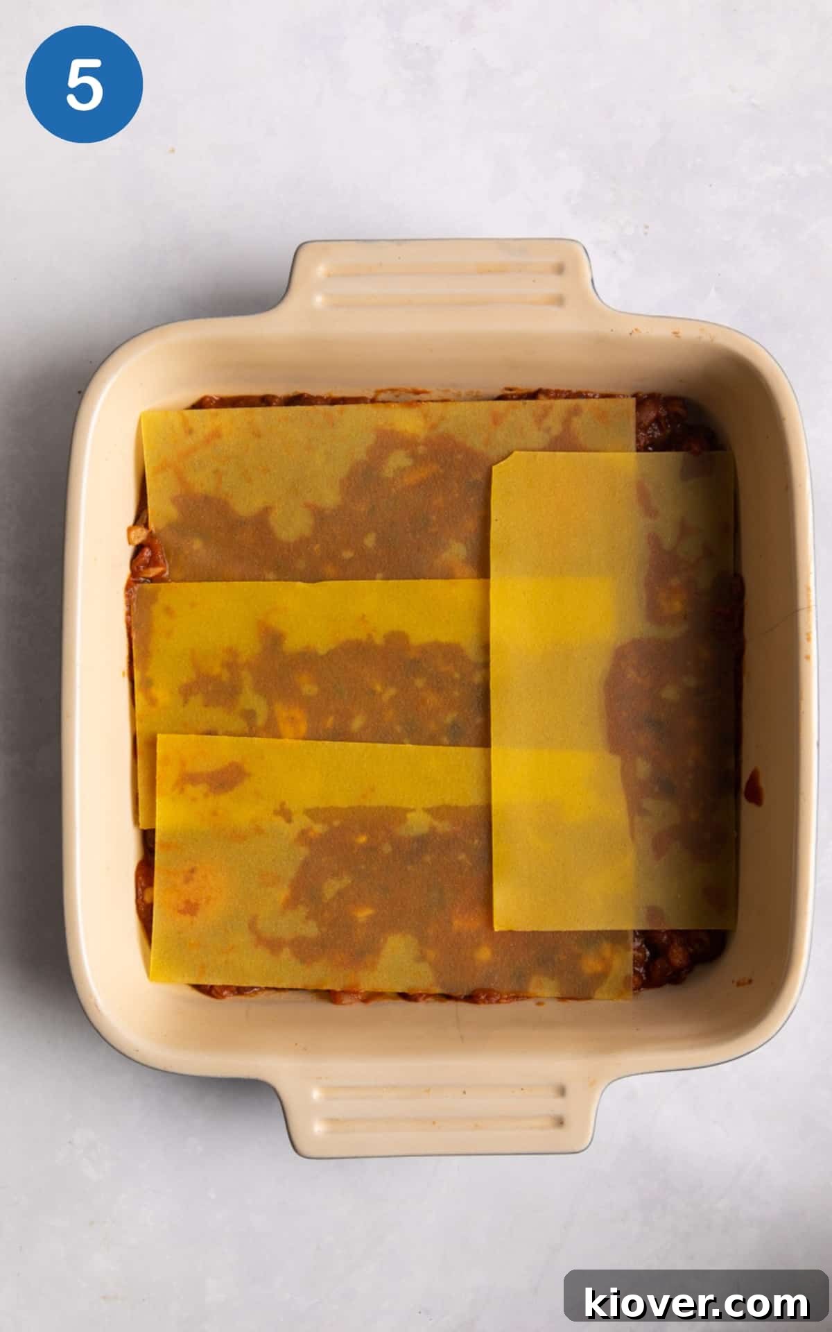 Creamy Vegan Lasagna with Spinach and Cashew Ricotta 8 lasagne sheets being laid in large baking tray on white surface.