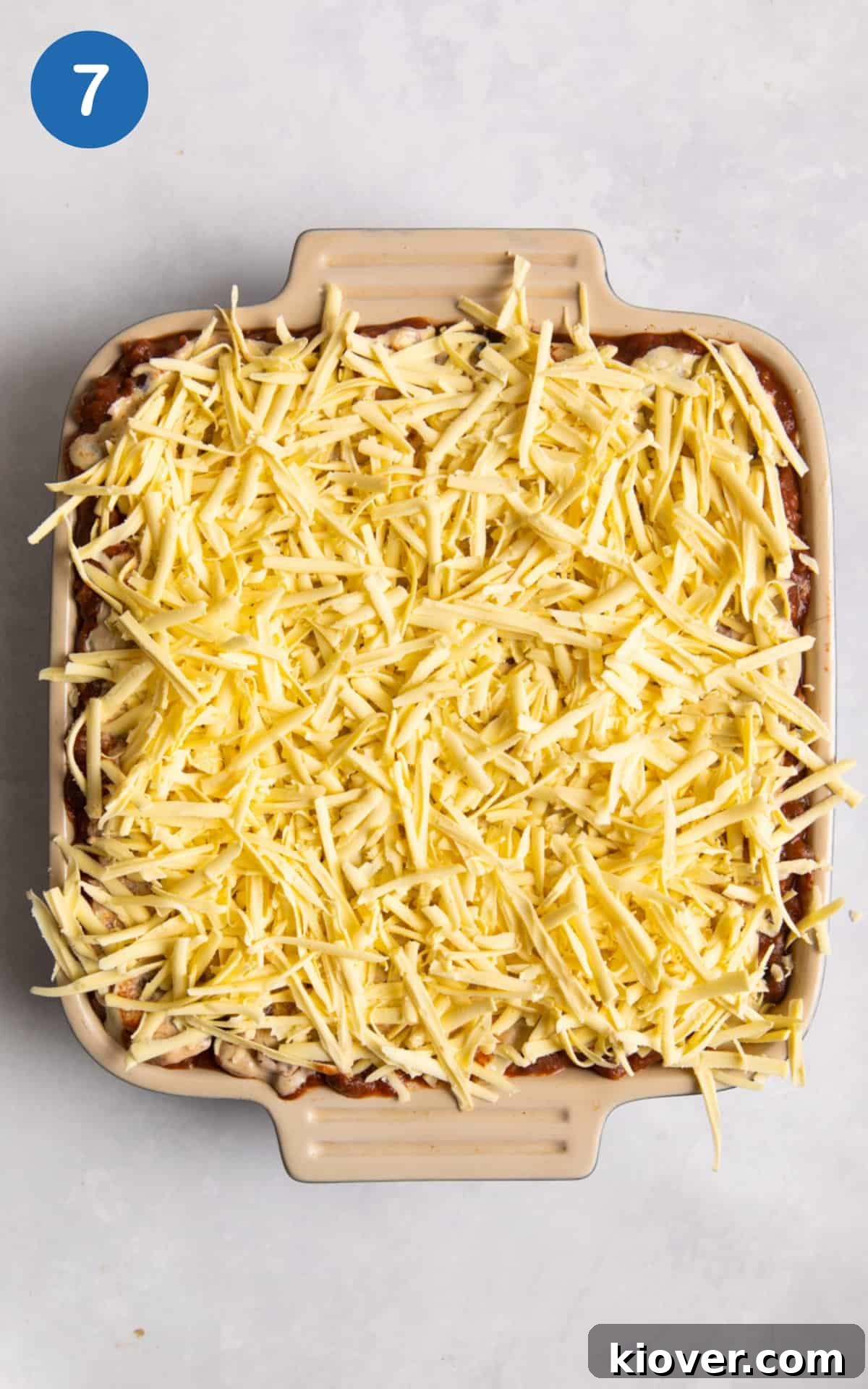 Creamy Vegan Lasagna with Spinach and Cashew Ricotta 10 overhead shot of lasagne with grated cheese on top. Baking tray is on white surface.