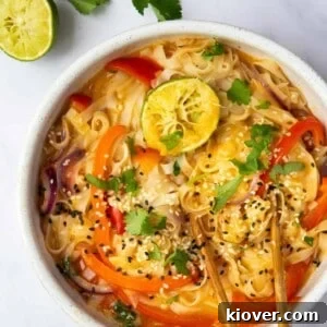 Thai Curry Noodle Soup Recipe — Creamy Thai Coconut Noodle Bowl 13 Thai Curry Noodle Soup in a bowl with chopsticks, displayed on a white marble background with lime and coriander.