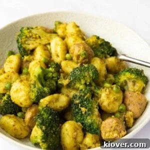 Creamy Sausage Pesto Gnocchi Recipe 14 Image shows a close up of Sausage Pesto Gnocchi served in a bowl with a white background.