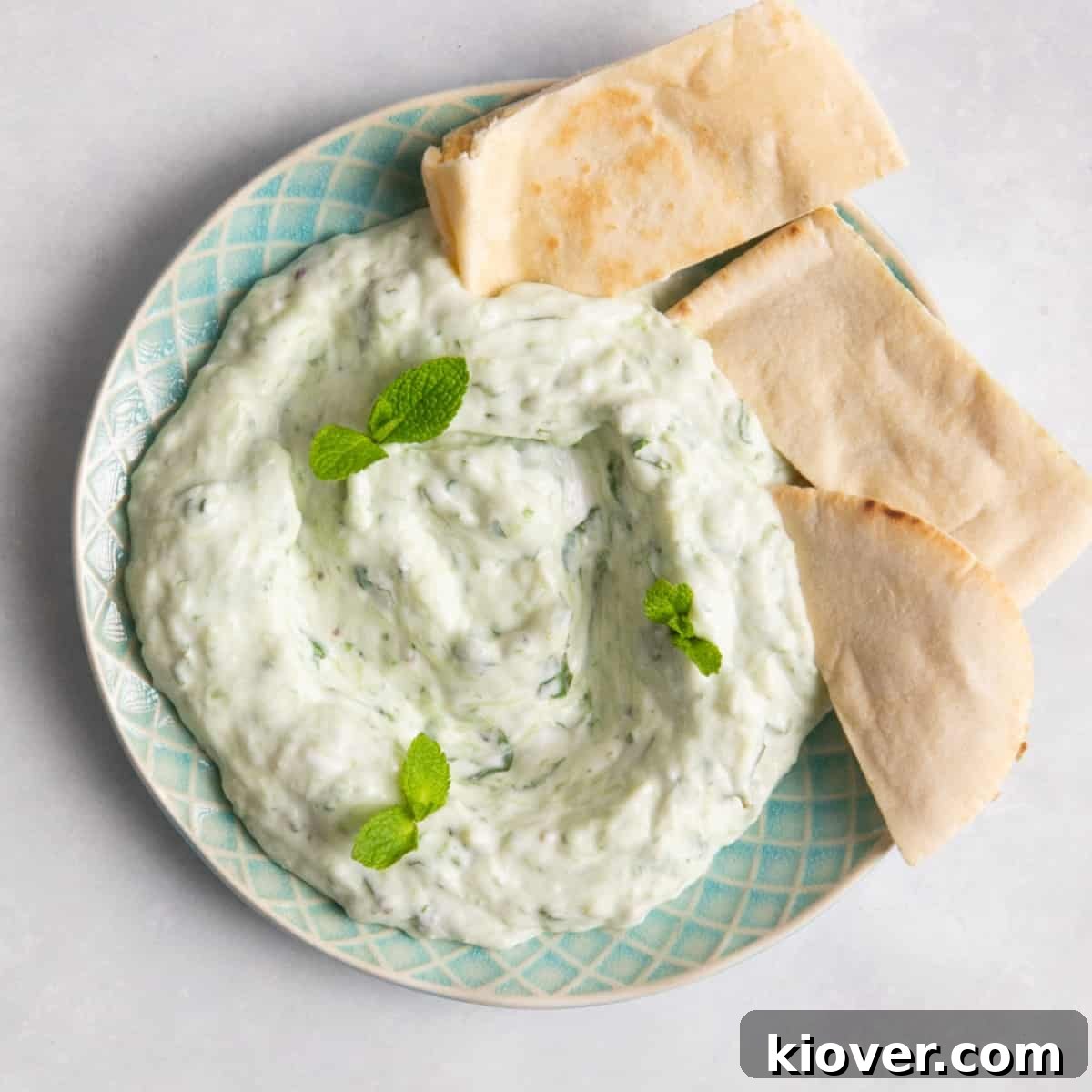 Creamy Vegan Tzatziki Sauce Recipe for Mediterranean Dishes 2 Tzatziki topped with fresh mint and accompanied with pitta bread on blue plate.