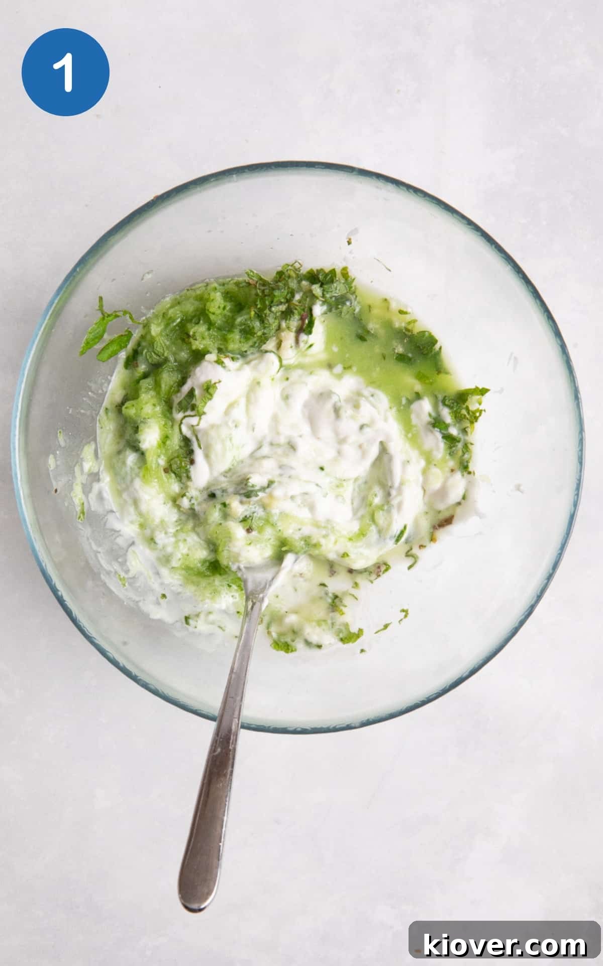 Creamy Vegan Tzatziki Sauce Recipe for Mediterranean Dishes 4 Tzatziki ingredient in glass bowl. bowl is on white surface.