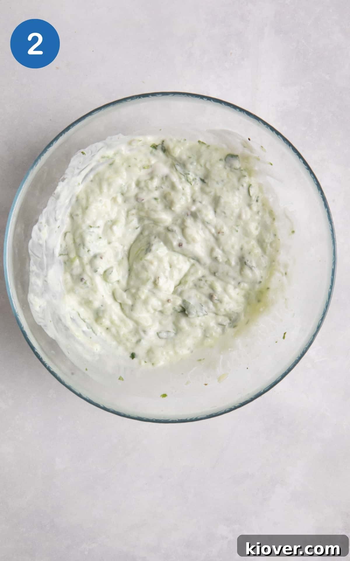 Creamy Vegan Tzatziki Sauce Recipe for Mediterranean Dishes 5 Tzatziki in clear glass bowl on white surface.