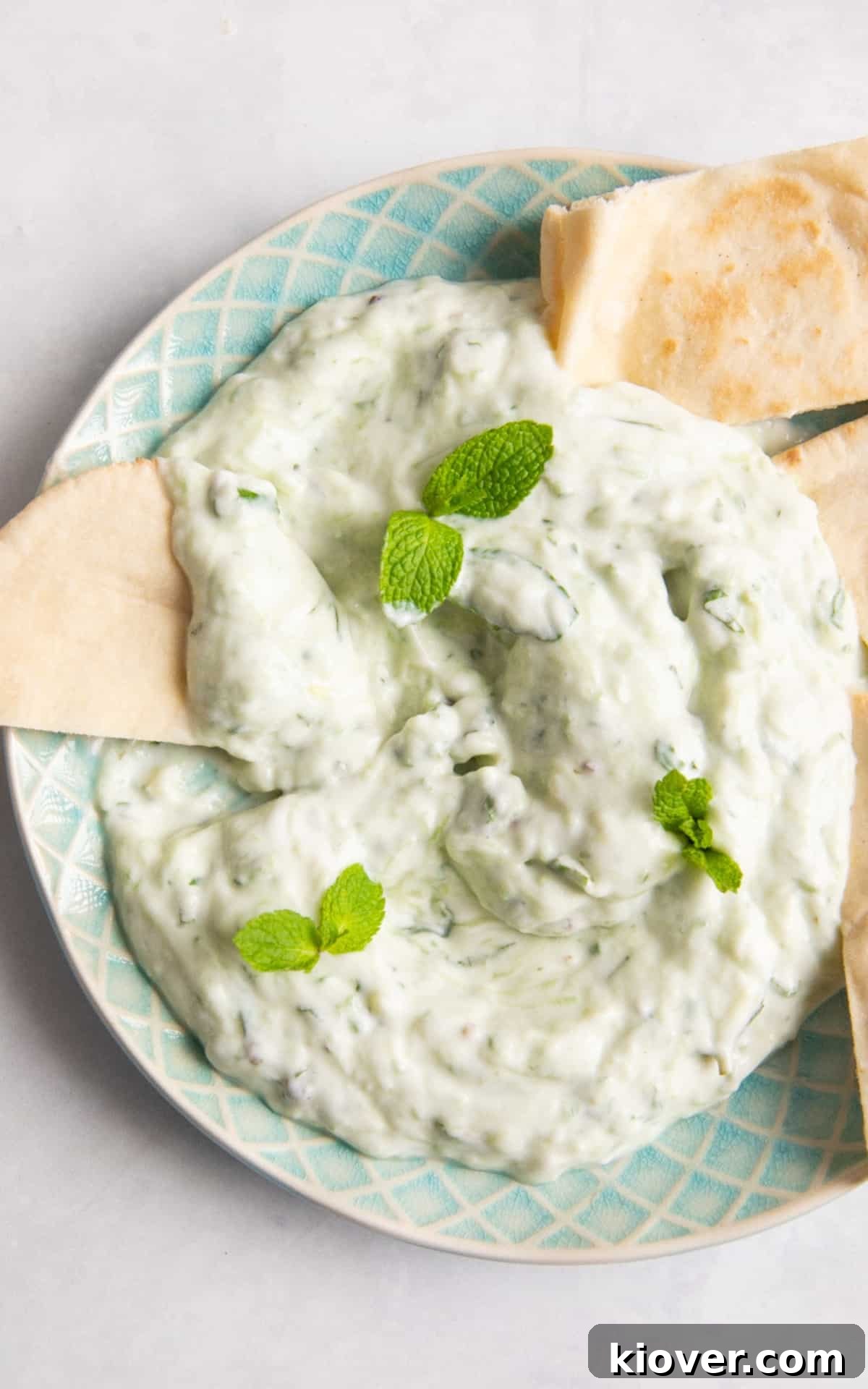 Creamy Vegan Tzatziki Sauce Recipe for Mediterranean Dishes 6 Tzatziki topped with fresh mint and pitta bread on blue plate.