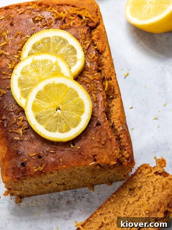 lemon drizzle cake topped with slices of lemon on concrete surface.