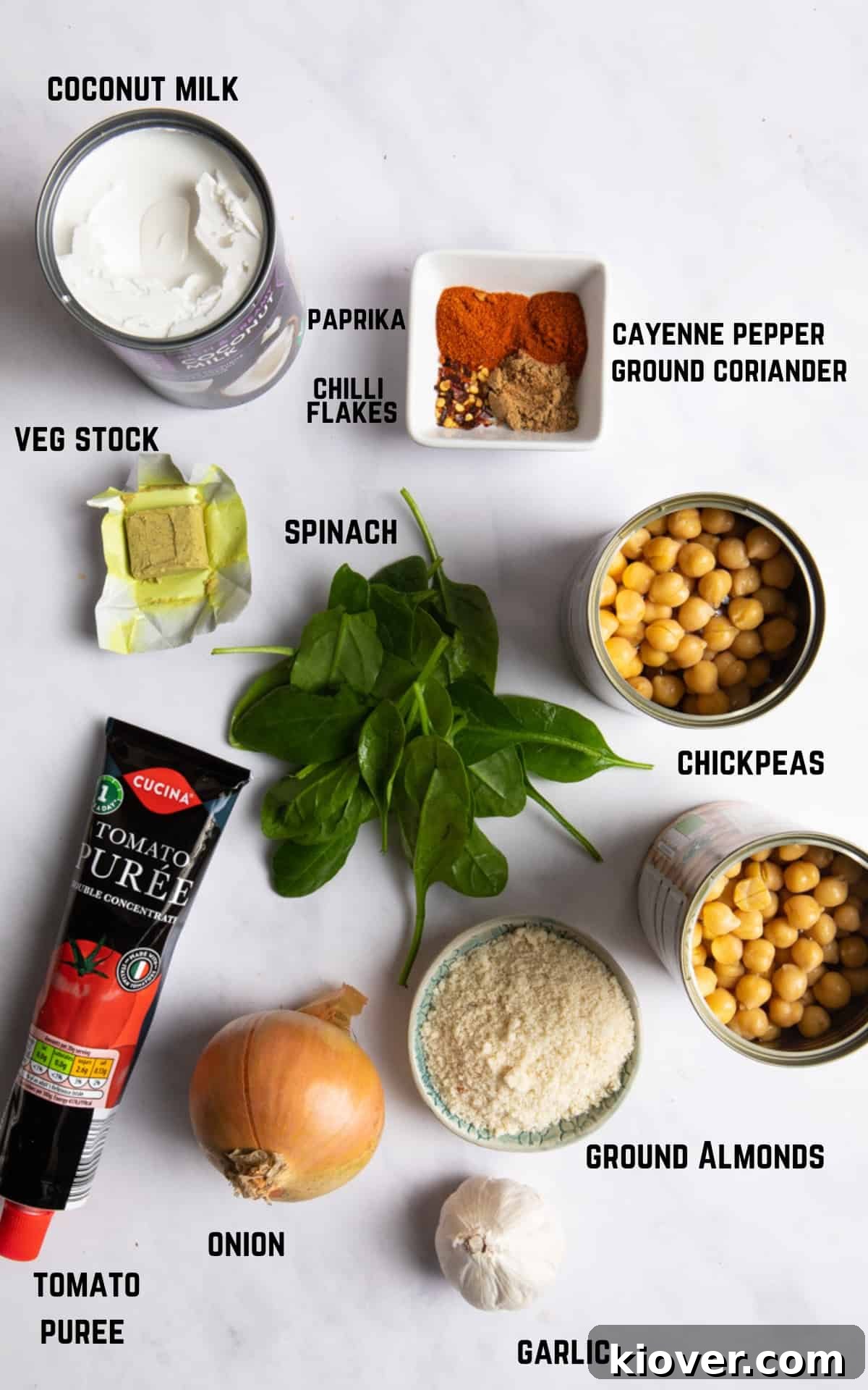 Ingredients to make chickpea curry laid on white marble background.