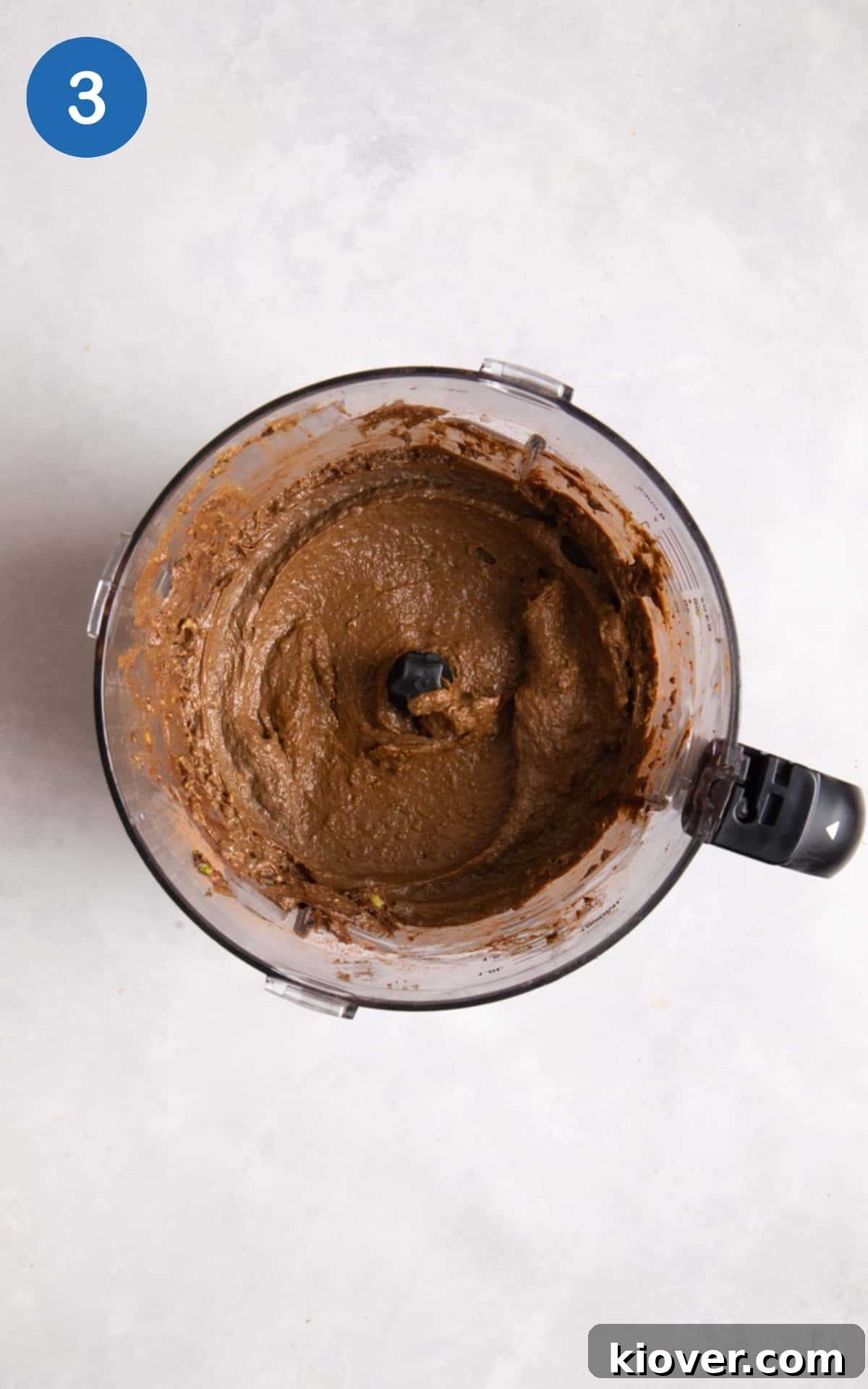 chocolate ganache filling being blended in bender. Blender is positioned on white background.