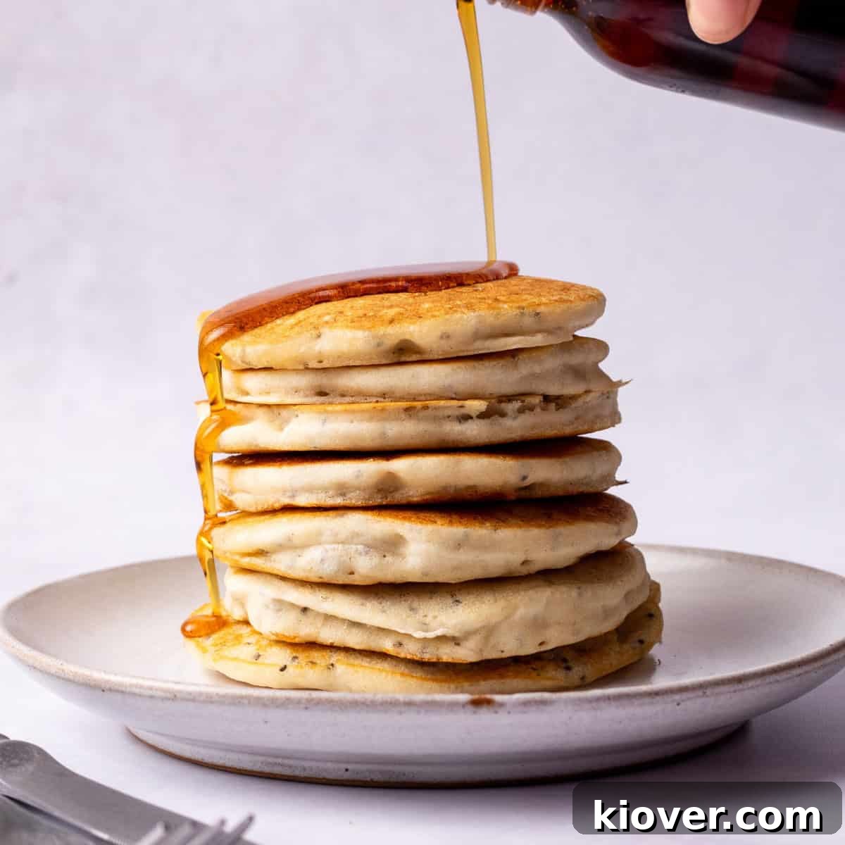 Fluffy Gluten-Free Pancake Recipe for Tender, Quick Breakfast 2 Pouring Maple syrup over gluten free pancakes.