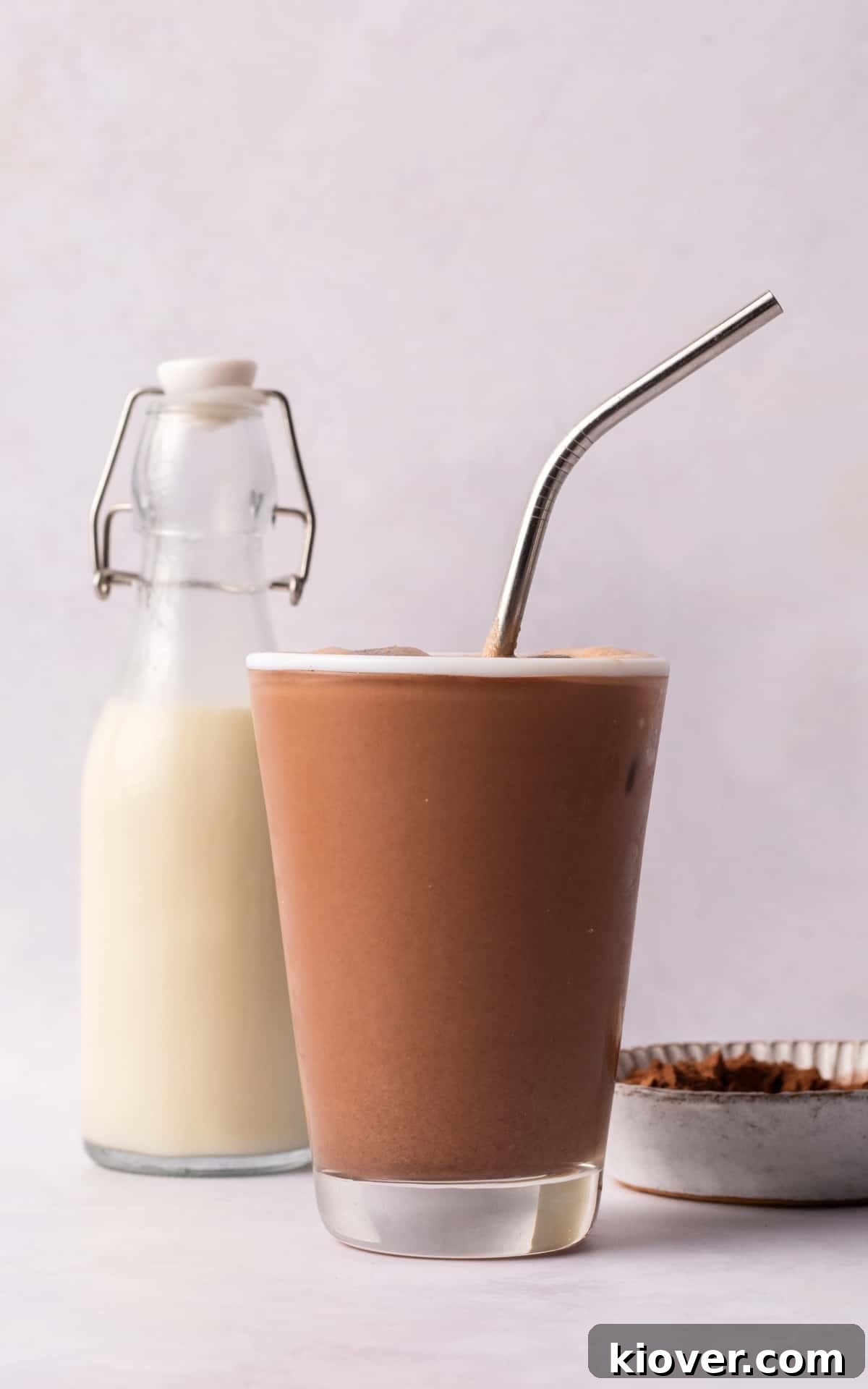 Peanut Butter Milkshake in a glass with a straw and a glass bottle of almond milk.
