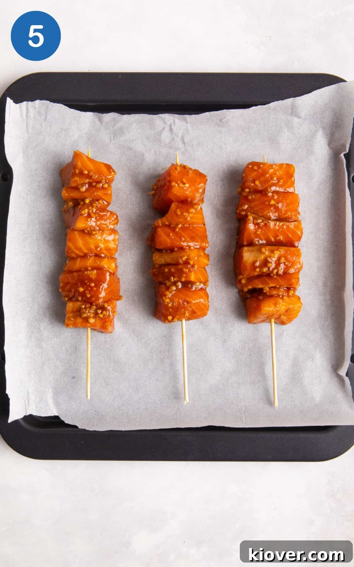 Salmon skewers on a parchment paper ready for oven. 