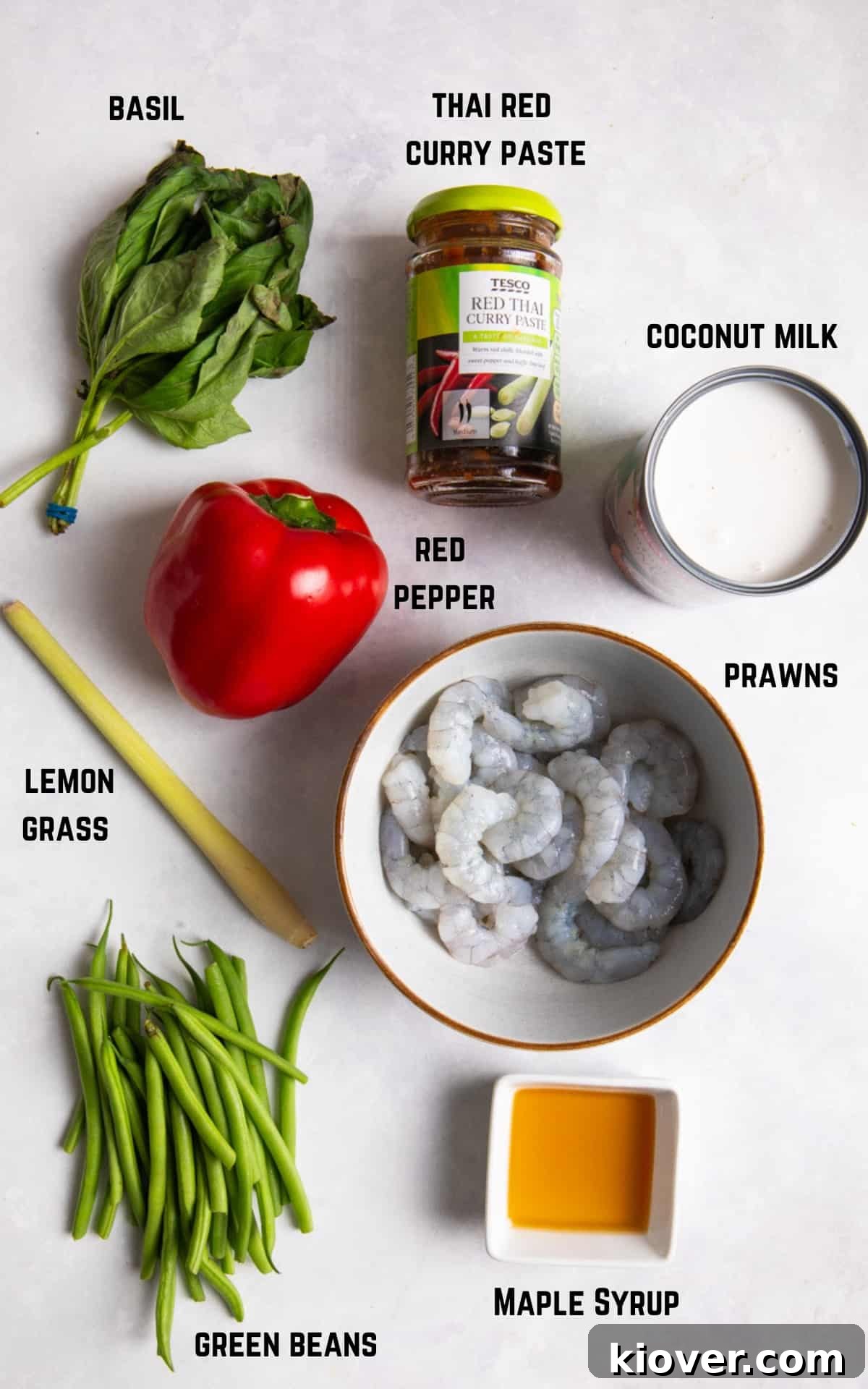 ingredients to make prawn curry displayed on white marble background.