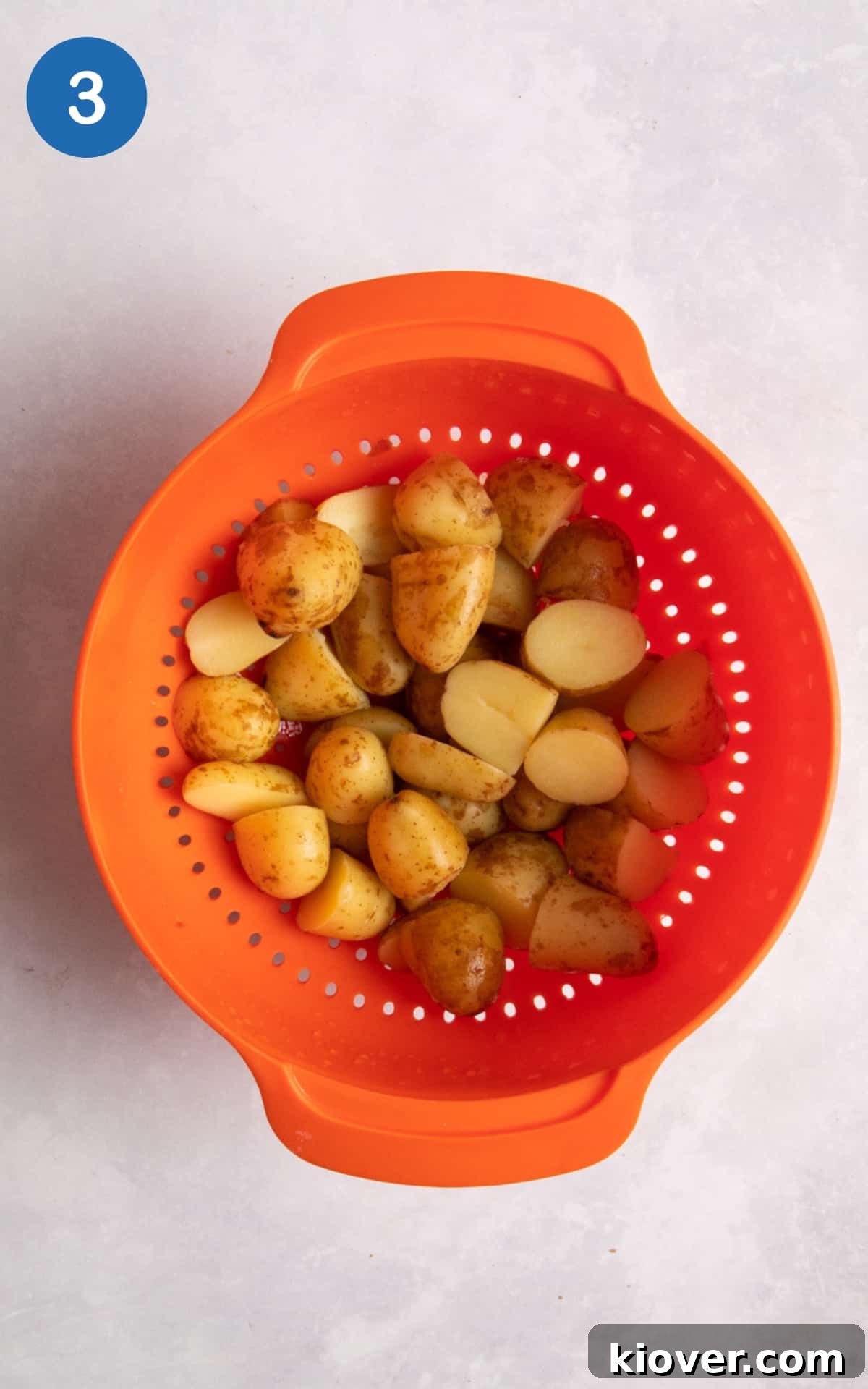 Creamy Yogurt Potato Salad with Fresh Herbs 6 new potatoes in orange colander on white surface.