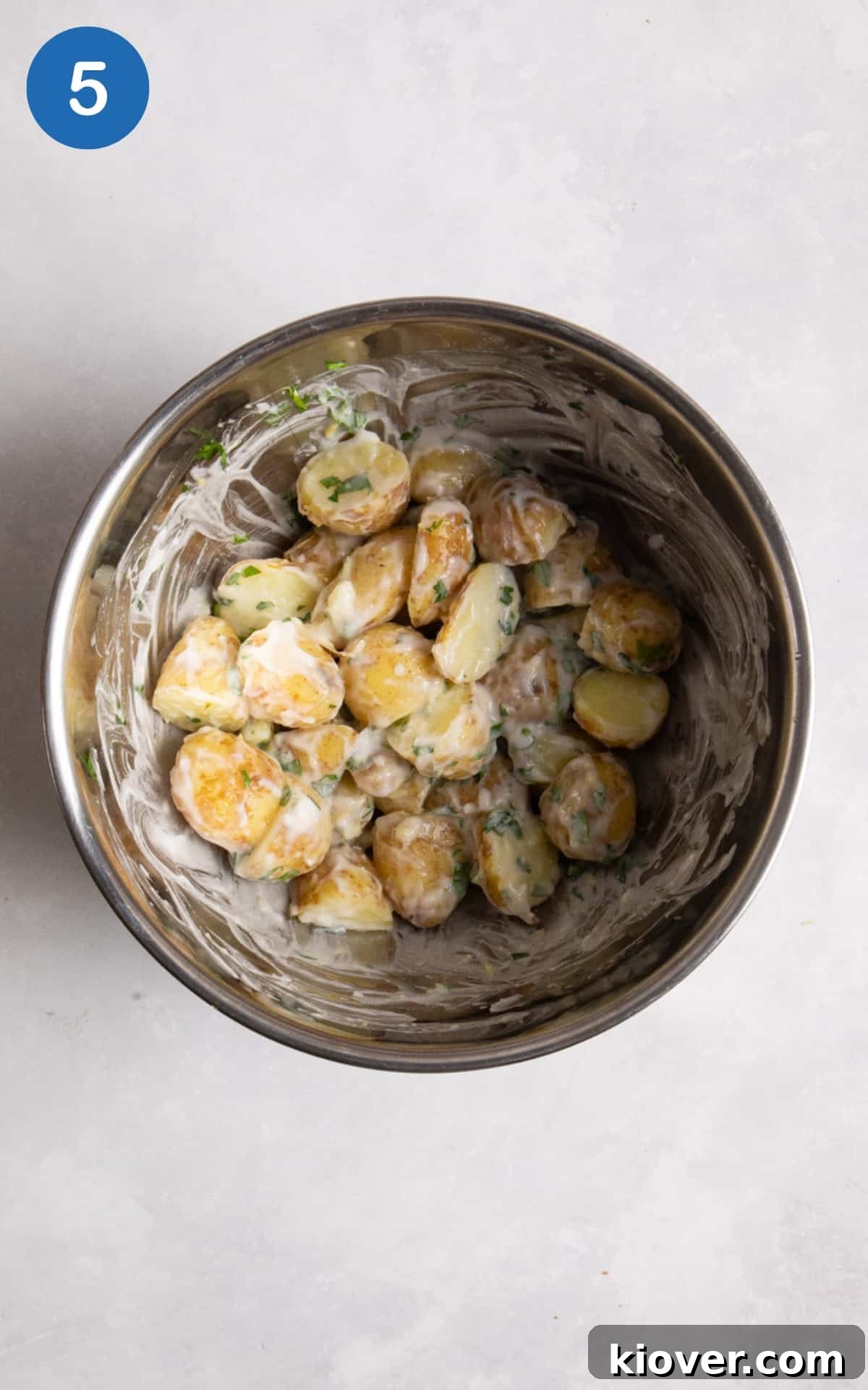 Creamy Yogurt Potato Salad with Fresh Herbs 8 potato salad in large silver mixing bowl. mixing bowl is on white surface.