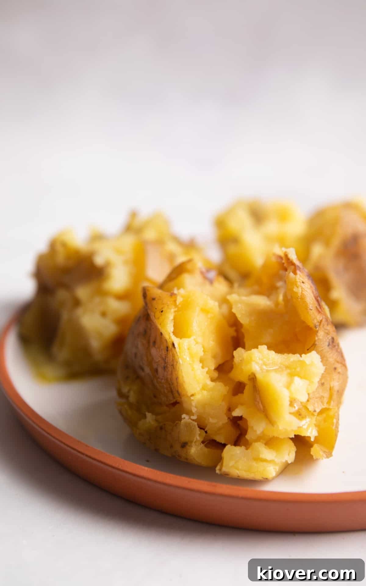 3 fluffy jacket potatoes cut open with melted butter inside.