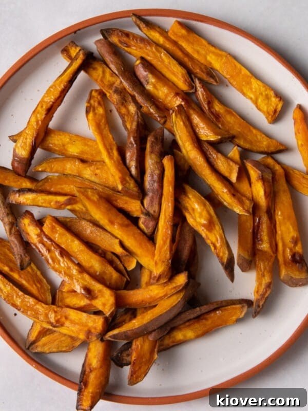Crispy Air Fryer French Fries: Quick Homemade Recipe 10 sweet potato fries on white plate with orange rim.