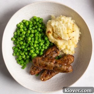 air fryer sausages in a bowl served with mash potato and peas.