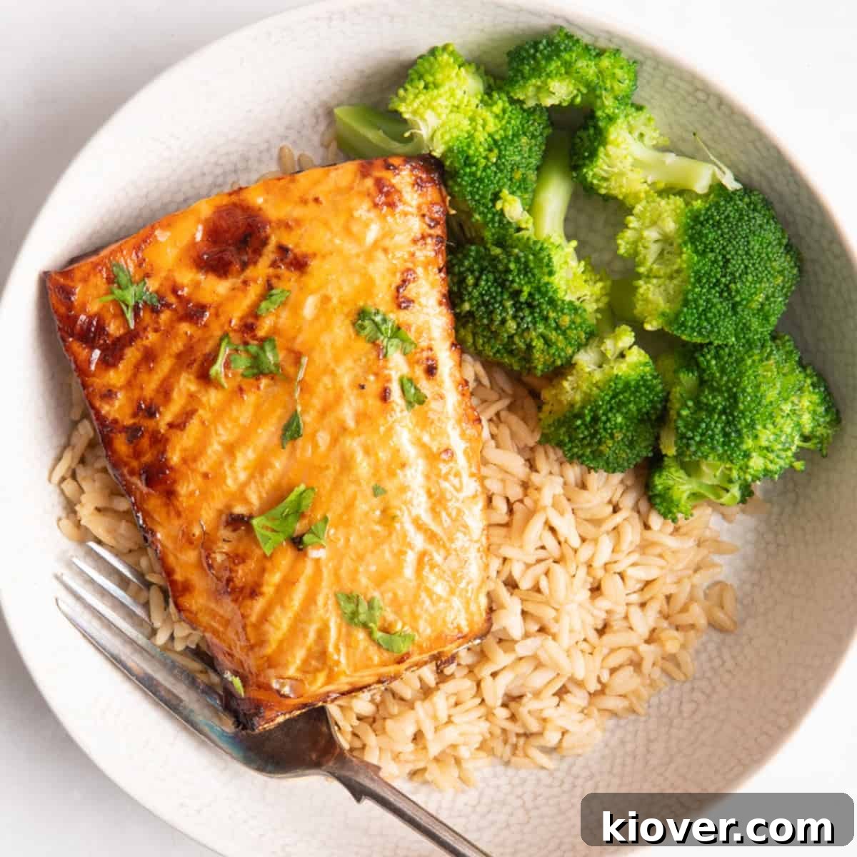 salmon fillet served on bed of rice with broccoli in white plate.