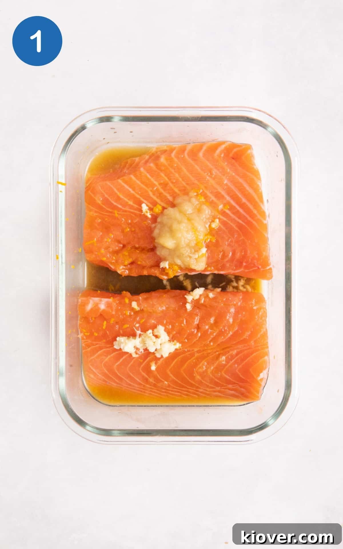 Salmon fillets in transparent container on white surface.