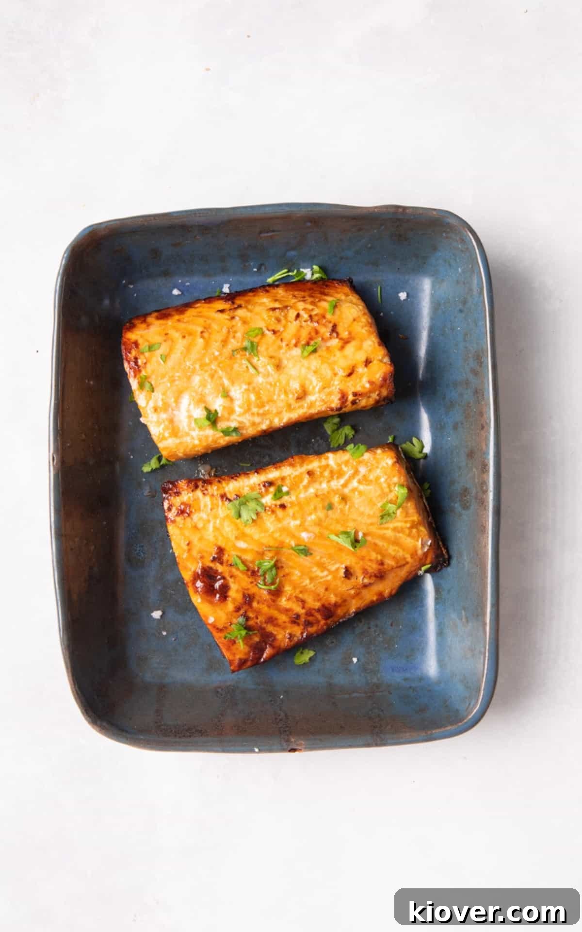 salmon fillets in blue dish on white surface.