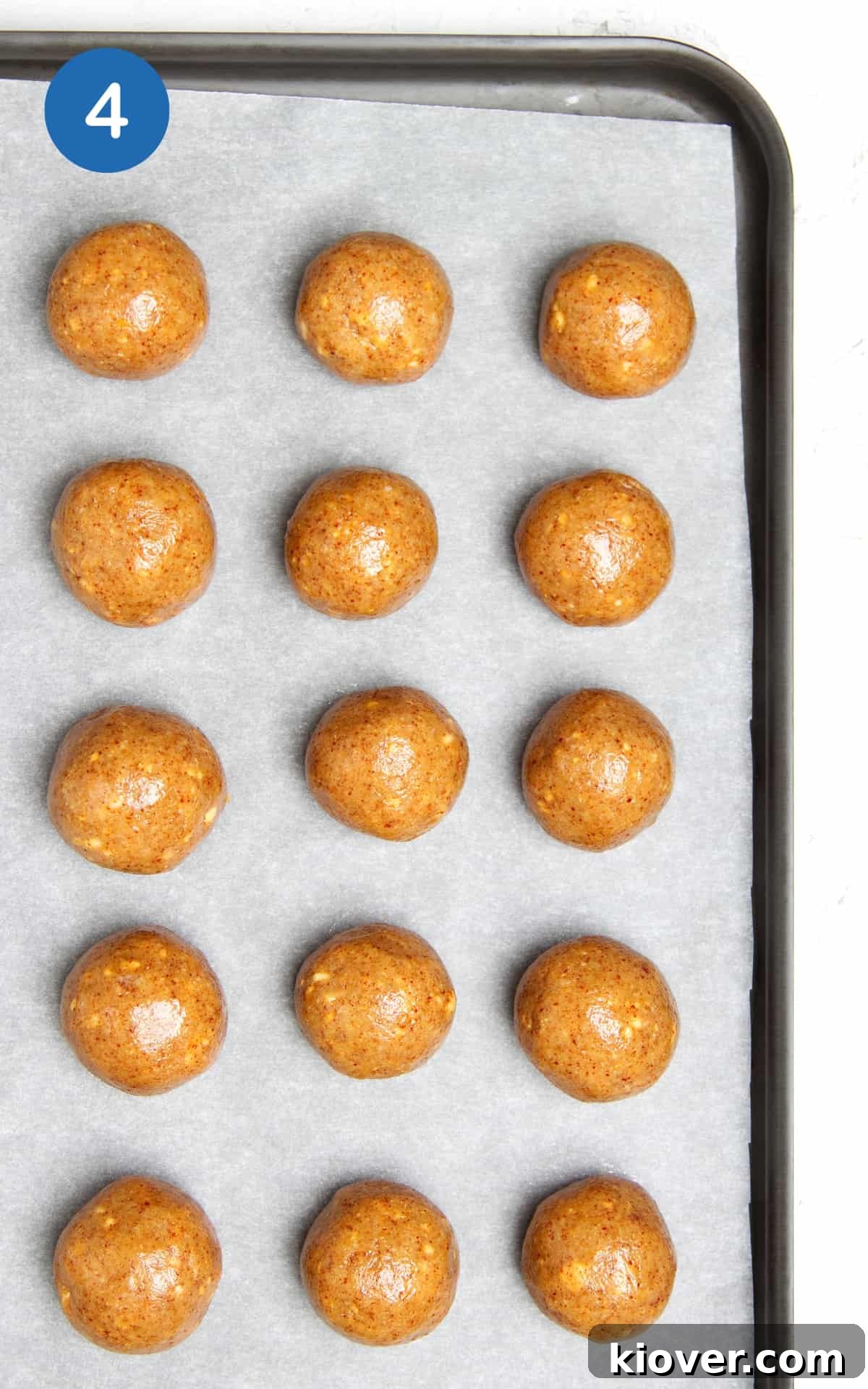 No-Bake Peanut Butter Protein Balls for Snacks & Desserts 7 smooth peanut butter balls on a tray lined with baking paper.